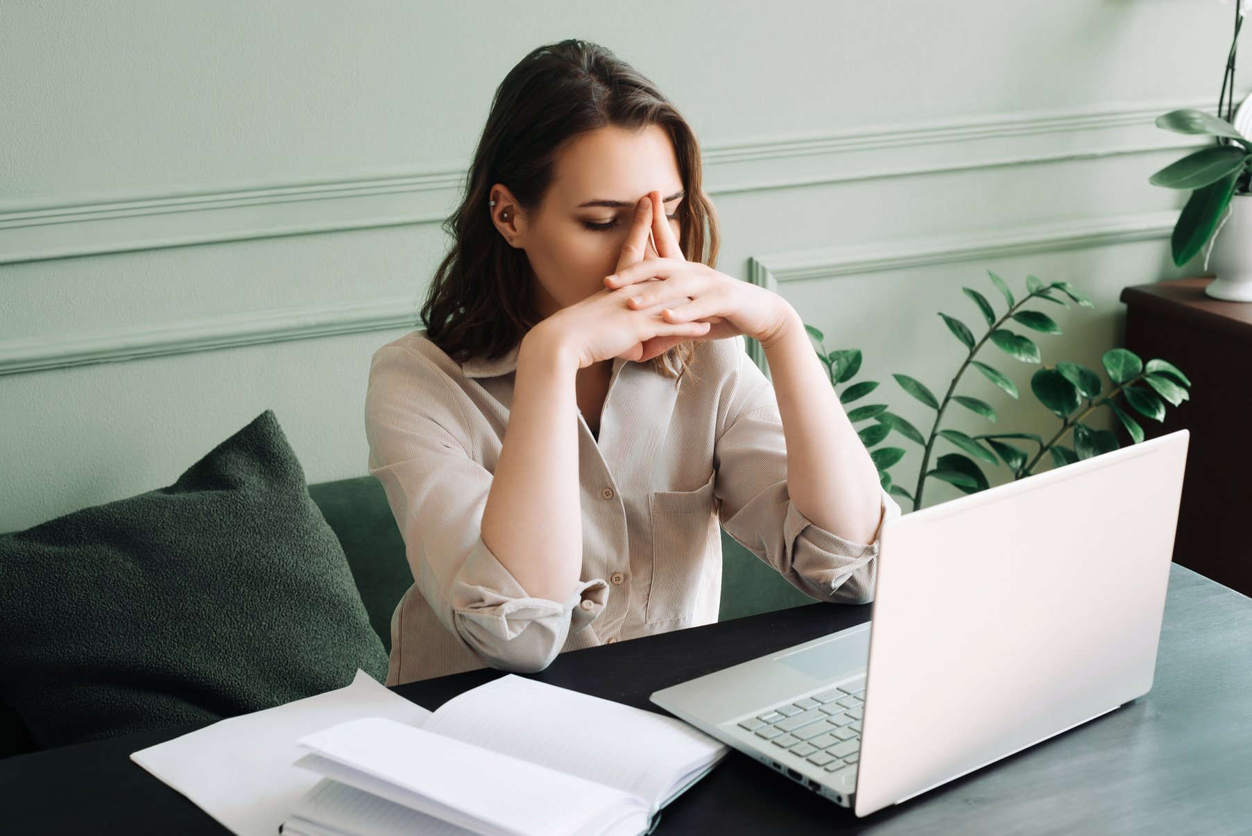 Fatigued and Dismal Young Woman Struggling with Overexertion While Staring at Computer. Weary Young Woman in Distress: Overexerted and Gloomily Contemplating at Her Computer